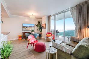 A modern living room with a large window, a dining area, and a balcony with a view. - Bright 1BR in Coconut Grove King Bed, Views, Pool & Parking (Miami)