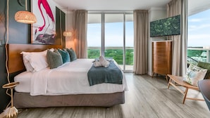 A hotel room with a large bed, a television, a balcony with a view, and a wooden floor. - Bright 1BR in Coconut Grove King Bed, Views, Pool & Parking (Miami)