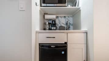 A compact kitchenette with a microwave, coffee maker, and a dishwasher.