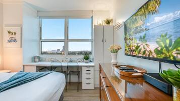 Een hotelkamer met een bed, een bureau, een televisie en een raam met uitzicht op de stad.