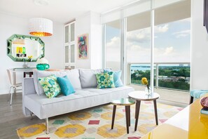 A modern living room with a sofa, a dining table, and a view of the city. - Private 2/2.5 bay View Apt. in Coconut Grove Hotel Includes Parking! (Miami)