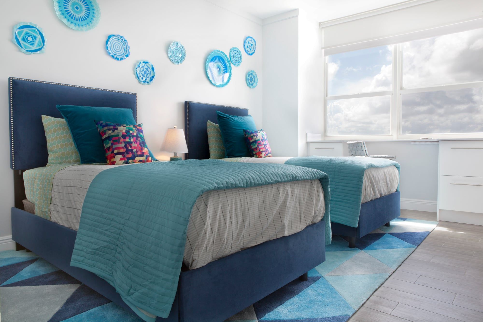A bedroom with two beds, a window, and decorative wall art.