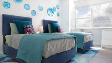 A bedroom with two beds, a window, and decorative wall art.