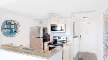 A modern kitchen with stainless steel appliances, a granite countertop, and a decorative wall piece.