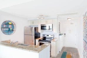 A modern kitchen with stainless steel appliances, a granite countertop, and a decorative wall piece. - Private 2/2.5 bay View Apt. in Coconut Grove Hotel Includes Parking! (Miami)