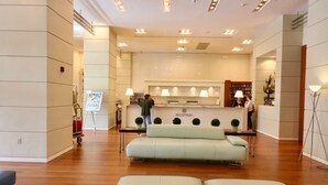 A hotel reception area with a reception desk, a sofa, and a floor lamp. - Coconut Grove:10th Fl Studio-parking Included (Miami)