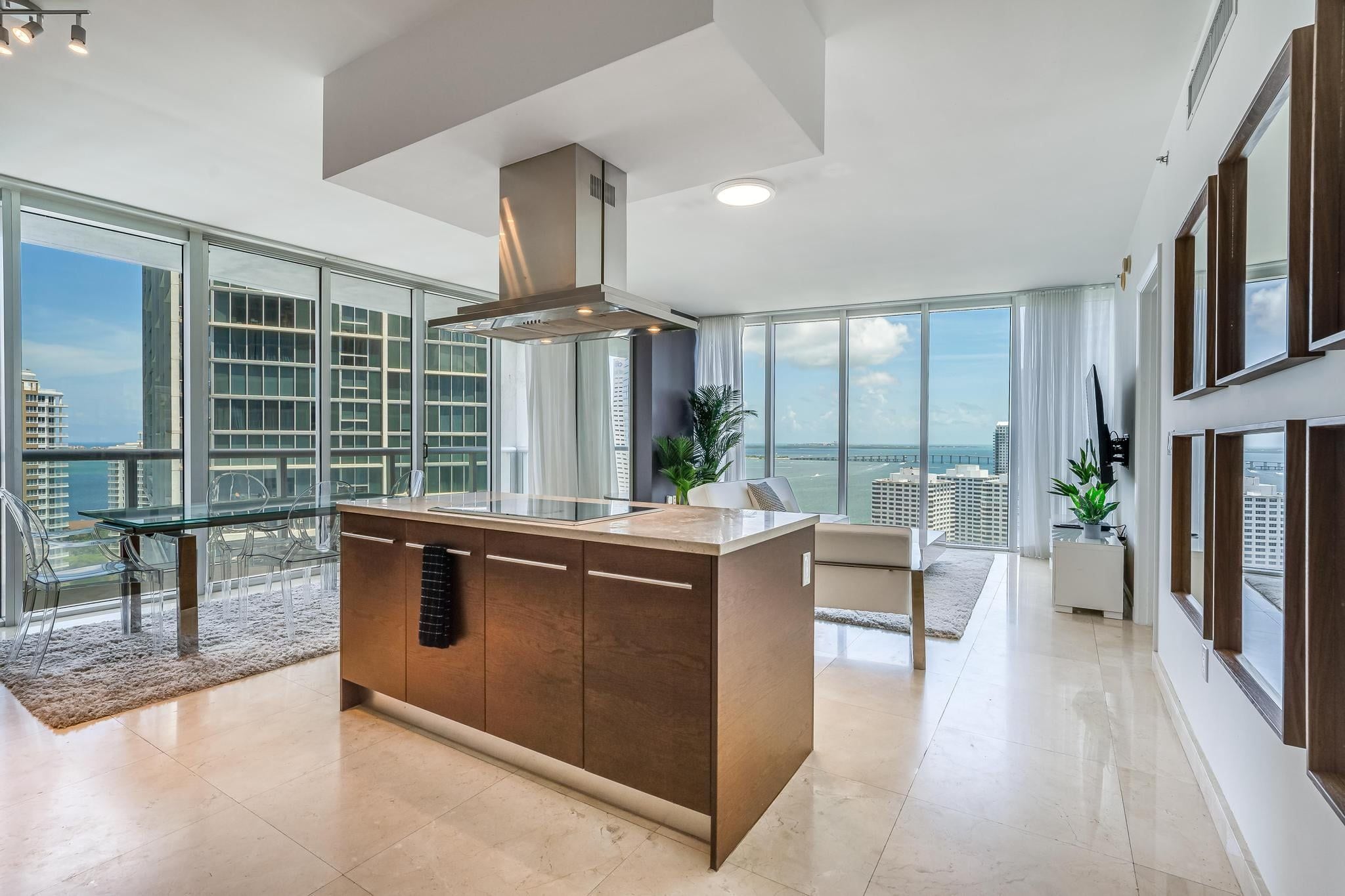 A modern kitchen with a central island, large windows, and a view of the cityscape.