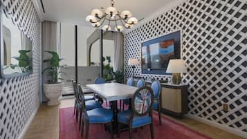Un espace repas comprenant une table, des chaises, un lustre, un téléviseur et un mur décoré d’un motif.