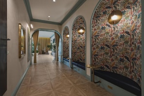 A hallway with patterned wallpaper, arched doorways, and a bench. - Walk to Wynwood Walls 1BR + Den 2 Baths (Miami)