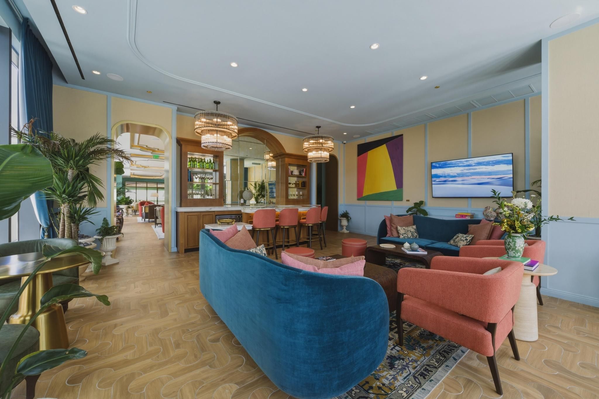 Un moderno vestíbulo de hotel con zona de bar, espacios para sentarse y una gran pantalla de televisión.