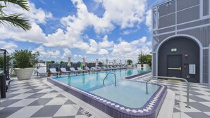 Un área de piscina con sillas de descanso, un jacuzzi y un edificio con una señal de salida.
