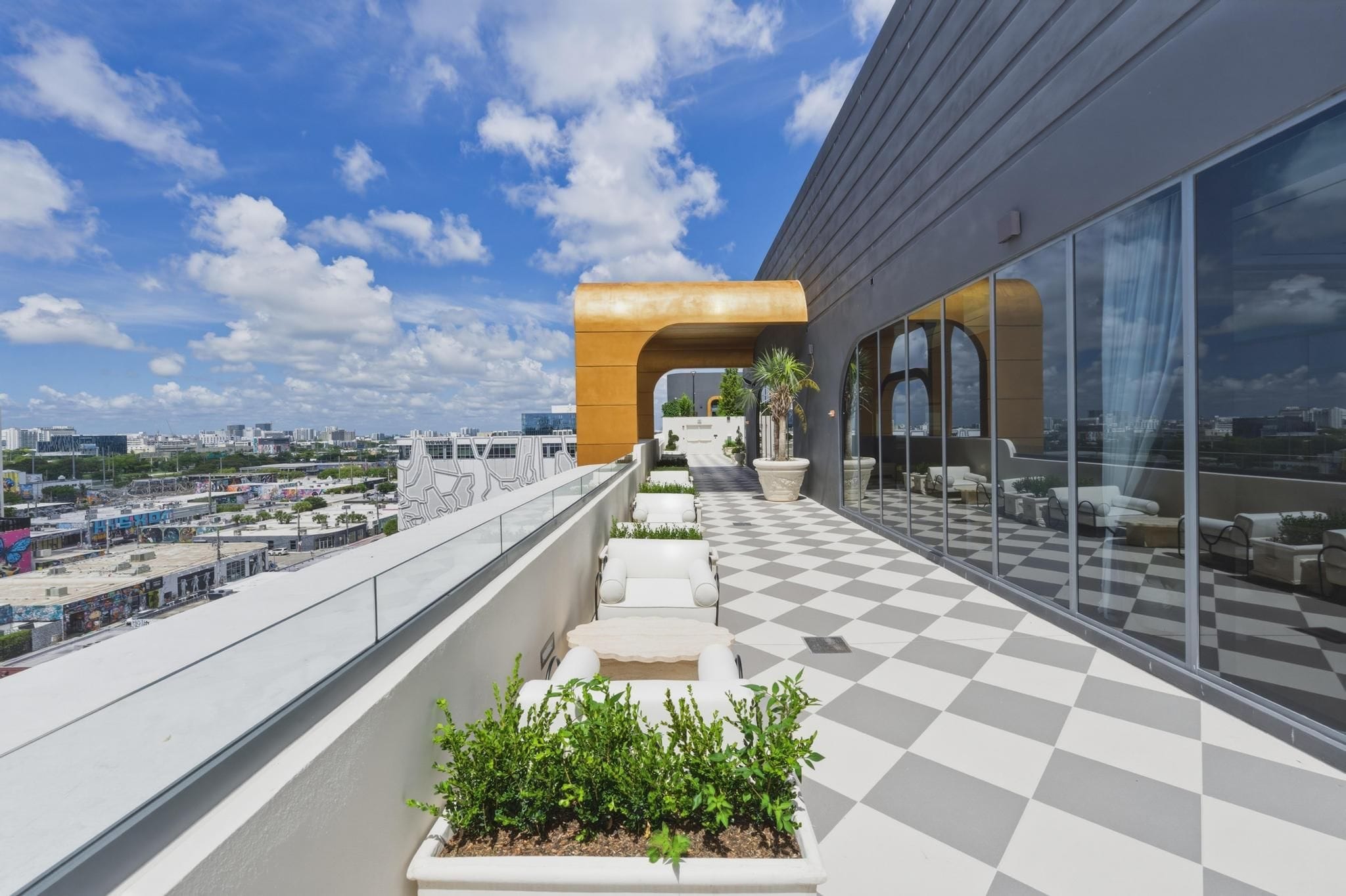 A rooftop terrace with a checkered floor, outdoor seating, and a view of the cityscape.