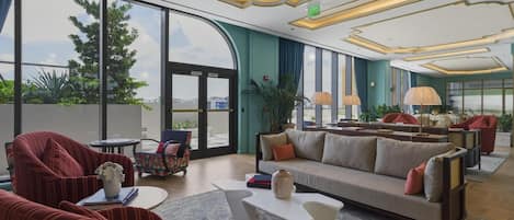 A spacious lobby with a sofa, chairs, a coffee table, and a large window offering a view of the outdoors.
