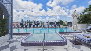 Pool på taget med liggestole og en bys skyline i baggrunden.
