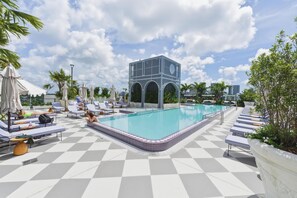 A pool area with lounge chairs, a pool, and a modern building with arches. - Luxury Wynwood 2BR Pool, Gym, Walk to Restaurants & Art (Miami)