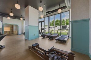 A gym with exercise equipment, large windows, and a wooden floor. - Luxury Wynwood 2BR Pool, Gym, Walk to Restaurants & Art (Miami)