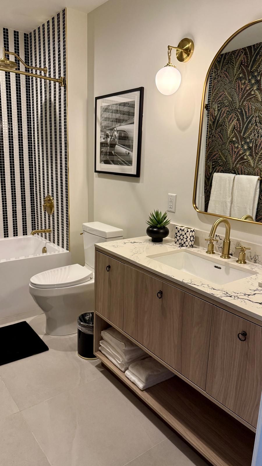 A modern bathroom with a bathtub, toilet, vanity with a mirror, and a framed picture on the wall.