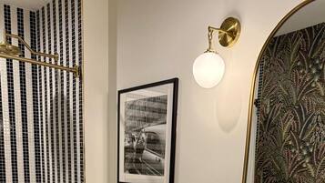 A modern bathroom with a bathtub, toilet, vanity with a mirror, and a framed picture on the wall.
