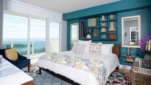 Un dormitorio con una cama grande, vista al mar y un balcón.