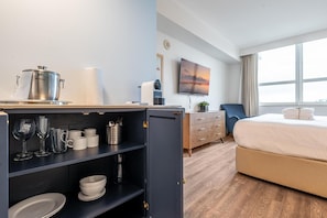 A hotel room with a bed, a desk with a kettle, a coffee machine, and a TV. - Cozy Grove Stay Free Parking, Pool Access, Walk to Cafés & Parks (Miami)