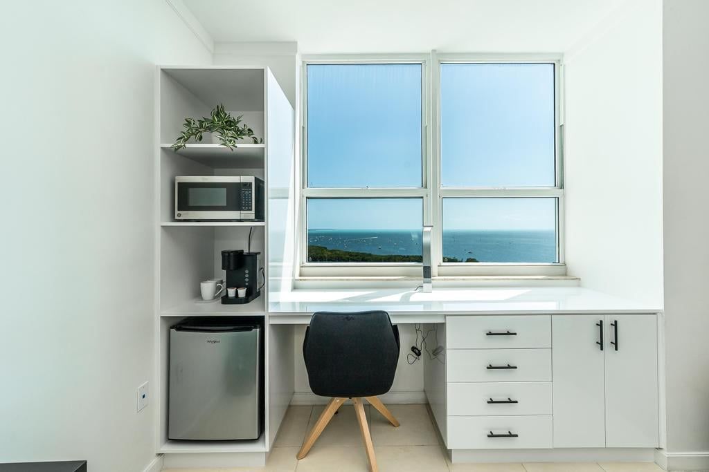 Una cucina moderna con forno a microonde integrato, macchina da caffè e frigorifero. Si vede una finestra con vista sul mare.