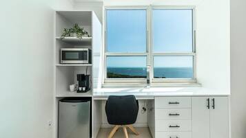Una cucina moderna con forno a microonde integrato, macchina da caffè e frigorifero. Si vede una finestra con vista sul mare.