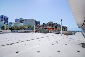 Terraza en la azotea con vistas al mar, que cuenta con una zona de estar con bancos y plantas en macetas.