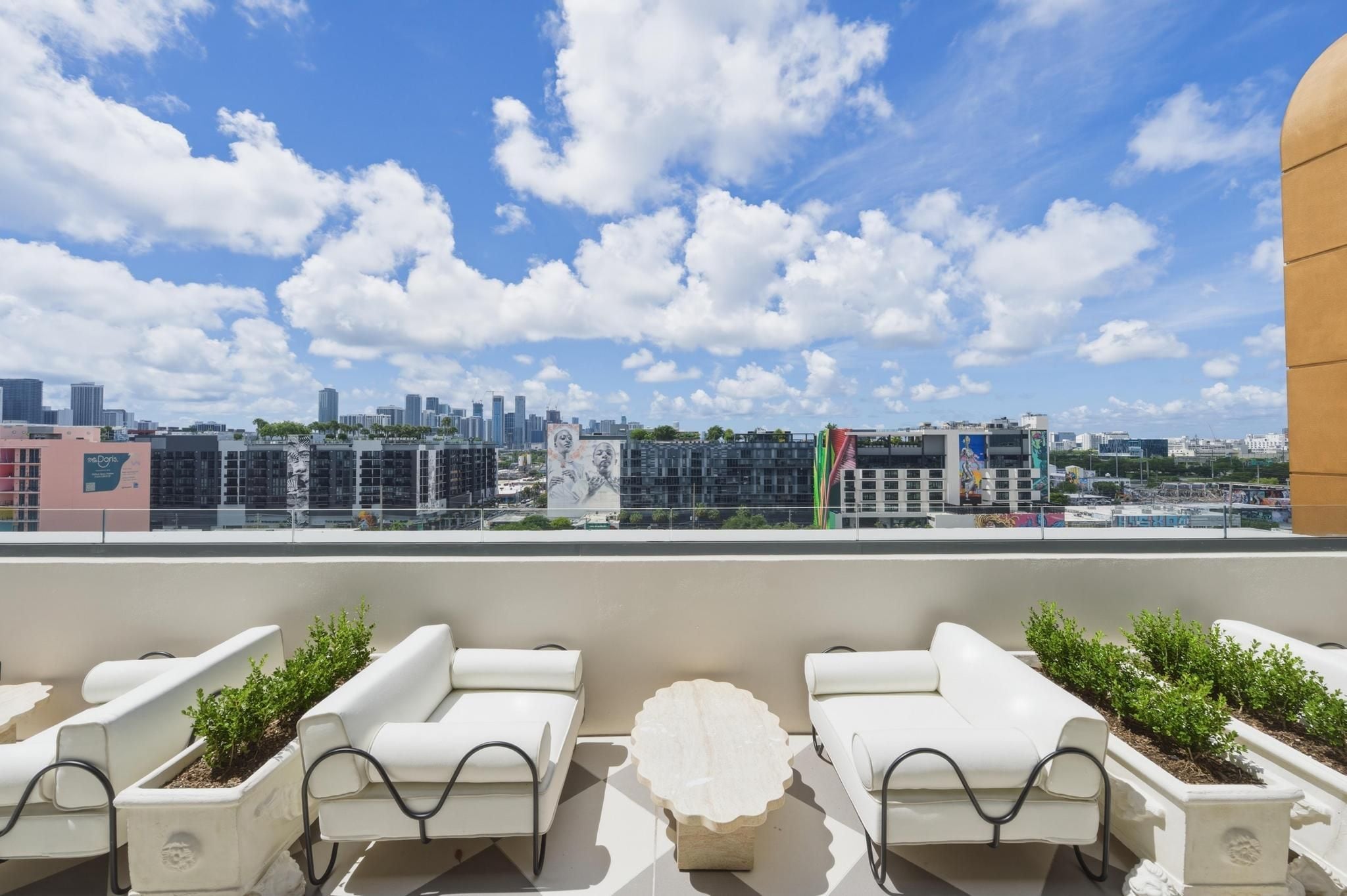 Una terraza en la azotea con sillones blancos, una mesa central y vistas a la ciudad.