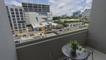 Uma varanda com vista para um horizonte urbano, incluindo edifícios modernos e uma rua com carros estacionados.