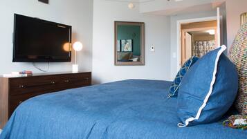 A bedroom with a bed, a television, a dresser, and a door leading to another room.
