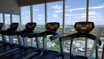 A gym with treadmills and a large window offering a city view.
