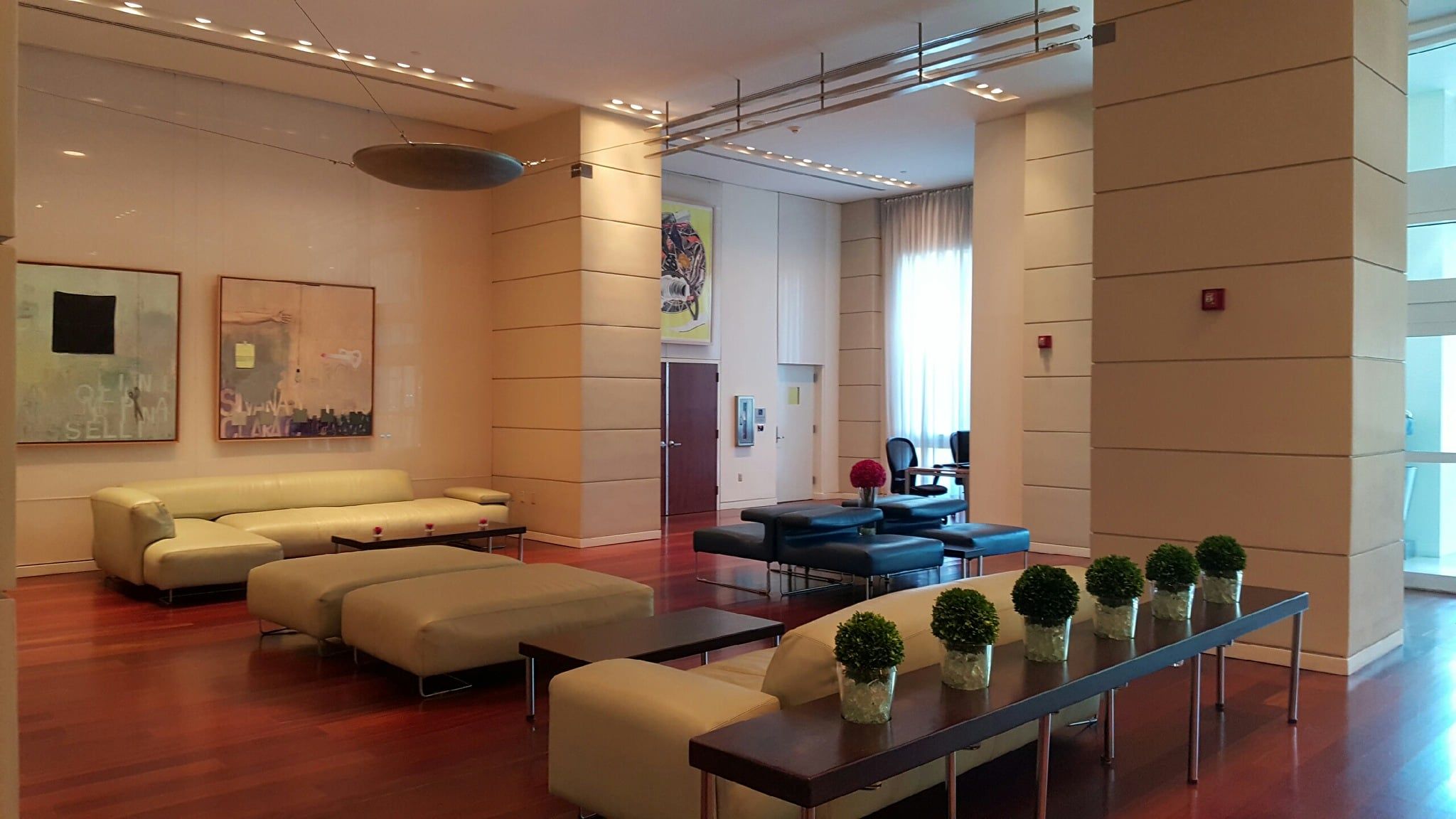 A modern lobby with sofas, a coffee table, and potted plants.