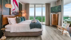A hotel room with a large bed, a television, a balcony with a view, and a wooden floor. - Elegant 2BR Condo at Hotel Arya Full Kitchen, Wraparound Views, Washer/dryer, 2 Parking Spots (Miami)