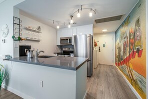 Uma cozinha moderna com ilha central, eletrodomésticos de aço inoxidável e um mural decorativo na parede.