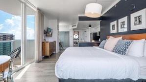 A modern hotel room with a large bed, a balcony with a table and chairs, a kitchen area, and a view of the city. - Modern Grove Studio Parking & Washer/dryer Included (Miami)