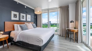 A modern hotel room with a large bed, a desk, and a view of the city. - Modern Grove Studio Parking & Washer/dryer Included (Miami)
