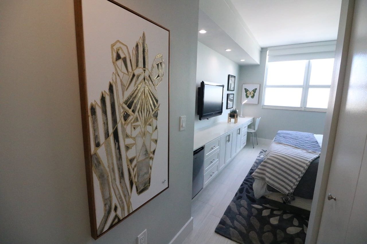 Une chambre à coucher comprenant un lit, un bureau, un téléviseur et des œuvres d’art accrochées au mur.