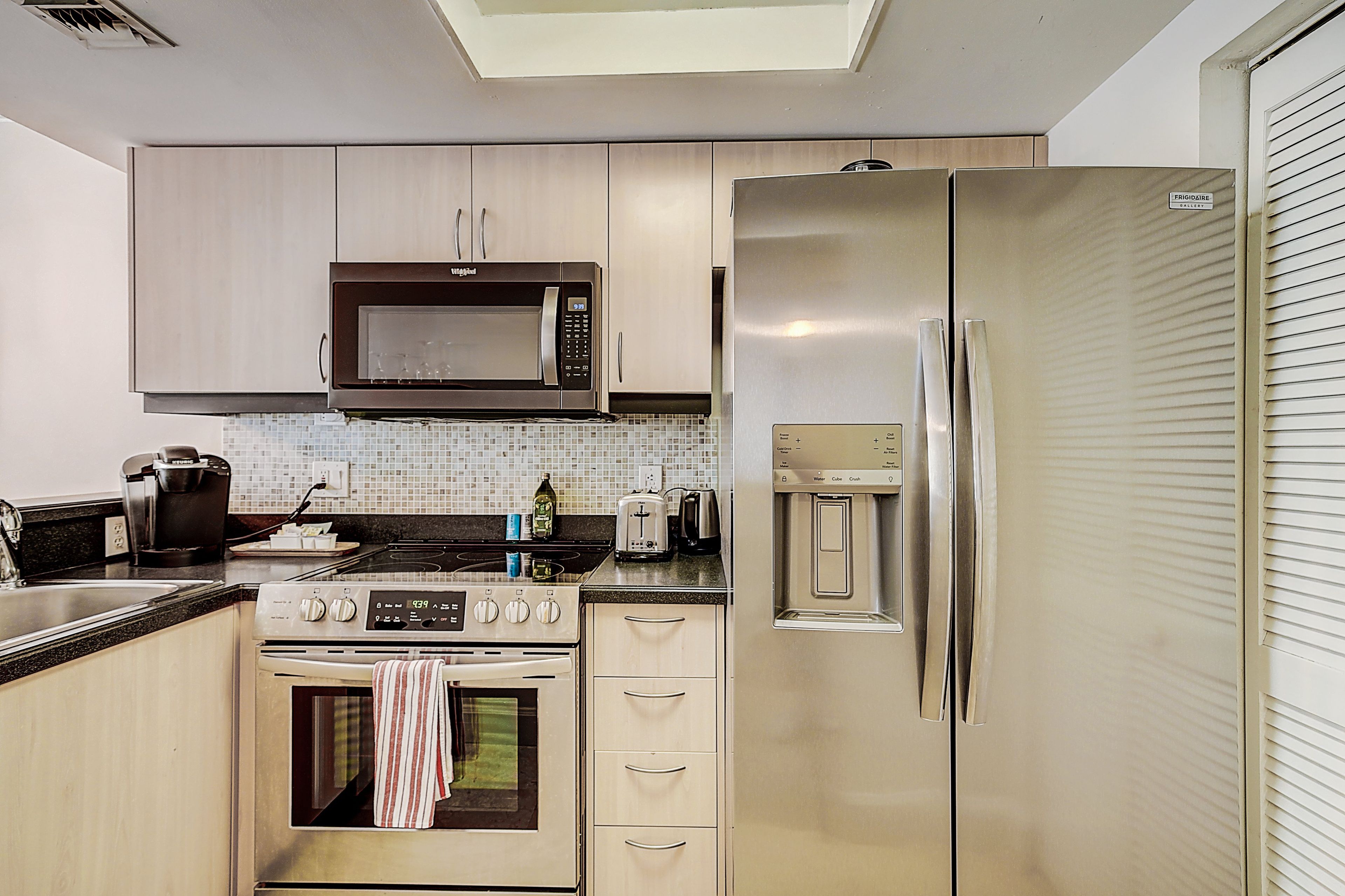 A modern kitchen with stainless steel appliances, including a microwave, refrigerator, and oven.