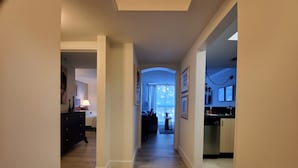 Een hotelgang met een houten vloer, een bed, een bureau en een kitchenette.