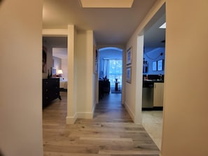 Ein Hotelkorridor mit Holzboden, einem Bett, einem Schreibtisch und einer Küchenzeile.