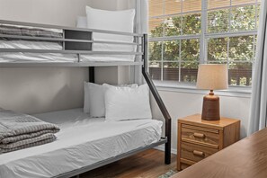 A bunk bed with white bedding, a bedside table with a lamp, and a window with blinds. - Cozy at the Cove - Pool Access (Branson)