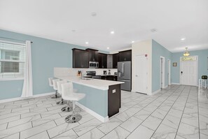 A modern kitchen with dark cabinets, a white countertop, and a marble floor. - Disney Area Villa with Private Pool Spa & Theater (Four Corners)