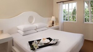 A hotel room with a bed, a tray with breakfast items, a nightstand, and a window with curtains. - 1BR VIP Residence Suites, All-Inclusive, Gold band, Puerto Plata, DR (Puerto Plata)
