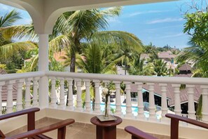 A balcony with a view of palm trees and a pool. - 1BR VIP Residence Suites, Gold band, All-Inclusive, Puerto Plata, DR (Puerto Plata)