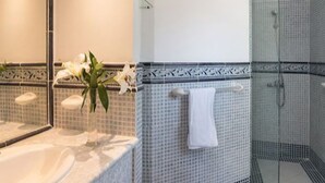A bathroom with a bathtub, a sink, a mirror, a towel rack, and a shower area. - 1BR VIP Residence Suites, All-Inclusive, Gold band, Puerto Plata, DR (Puerto Plata)