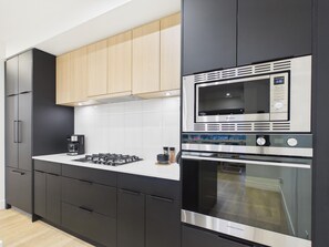 Una cocina moderna con armarios negros, una campana extractora de acero inoxidable, un microondas integrado y un horno doble.
