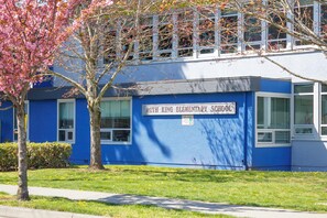 Ruth King Elementary School with a blue exterior, a signboard, and a tree with pink blossoms. - Scenic 3BR Mountain and Lake Haven in Bear Mountain (Langford)