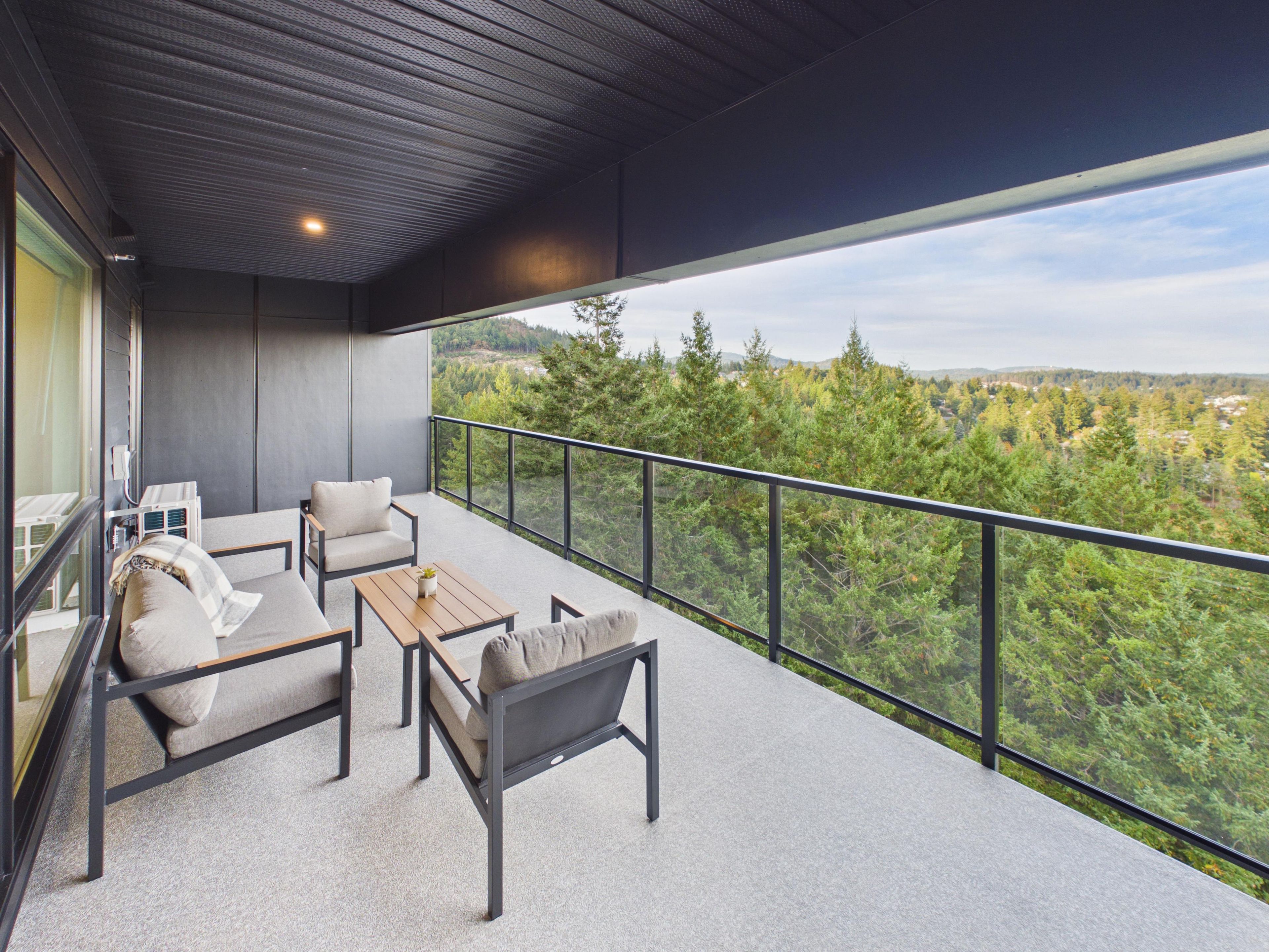 Een balkon met een bank, stoelen en een tafel.