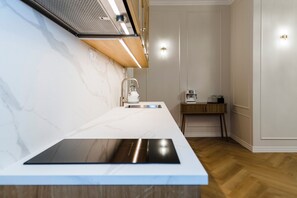 A modern kitchen with a built-in stove, a sink, and a coffee machine on a small wooden table. - Elegant Apartment | Fireplace | 20 min Old Town (Riga)