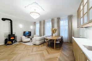 A modern living room with a fireplace, a dining area, and a kitchen. - Elegant Apartment | Fireplace | 20 min Old Town (Riga)